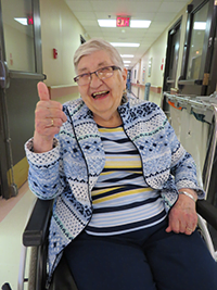 Smiling senior in wheelchair at a continuing care facility with thumbs up | HQCA