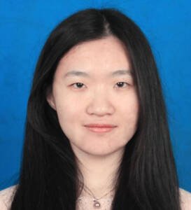 Jie is looking into the camera and smiling.