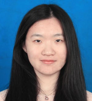 Jie is looking into the camera and smiling.